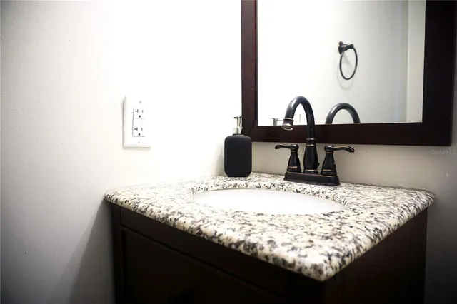a bathroom with a granite countertop sink and a mirror