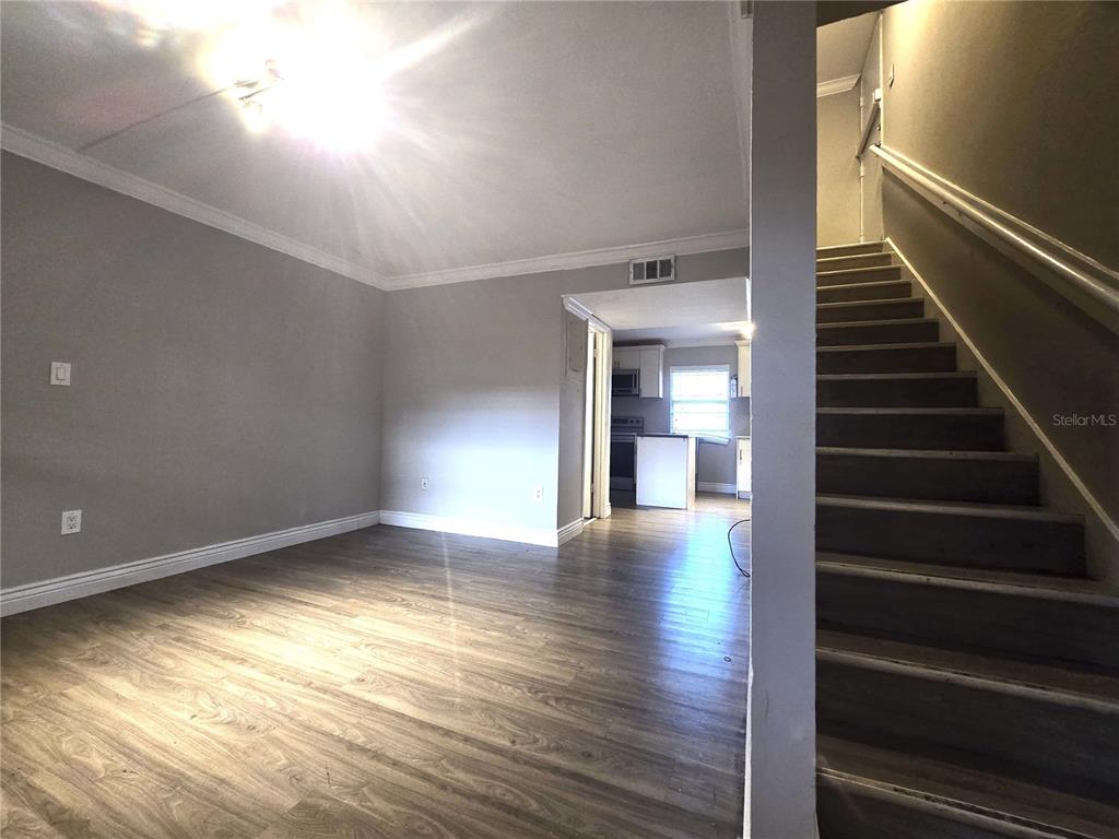 914 Southwest 8th Avenue, Unit 57 Gainesville, FL 32601 - Photo 6 of 31 a view of an empty room with wooden floor and stairs