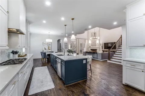 a large kitchen with kitchen island a stove a sink a refrigerator and a fireplace