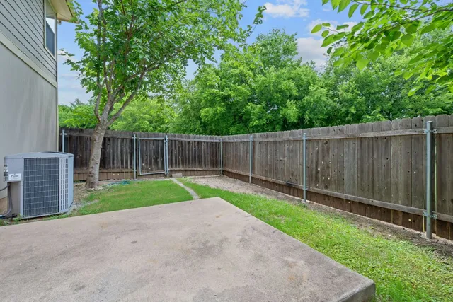 a view of a backyard with large trees and wooden fence