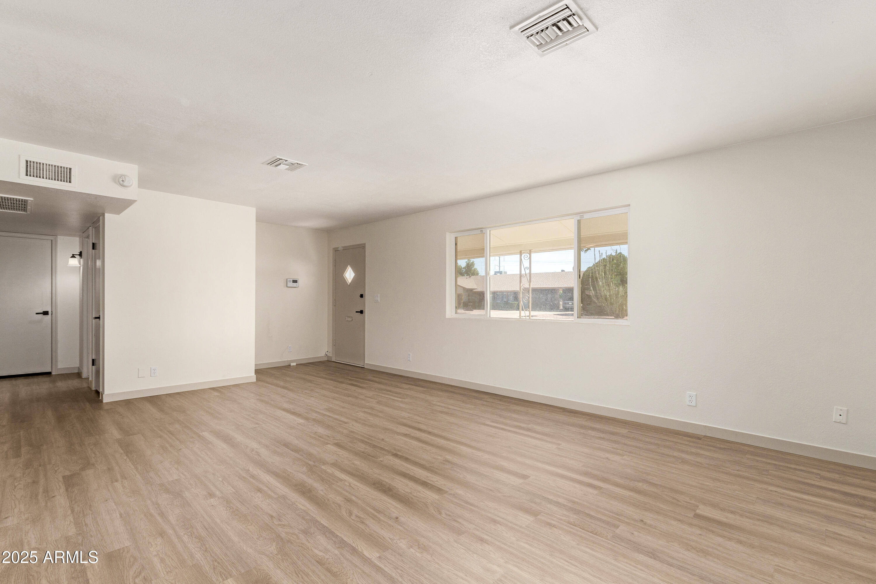 5732 Covina Road Mesa, AZ 85205 - Photo 5 of 24 an empty room with wooden floor and windows