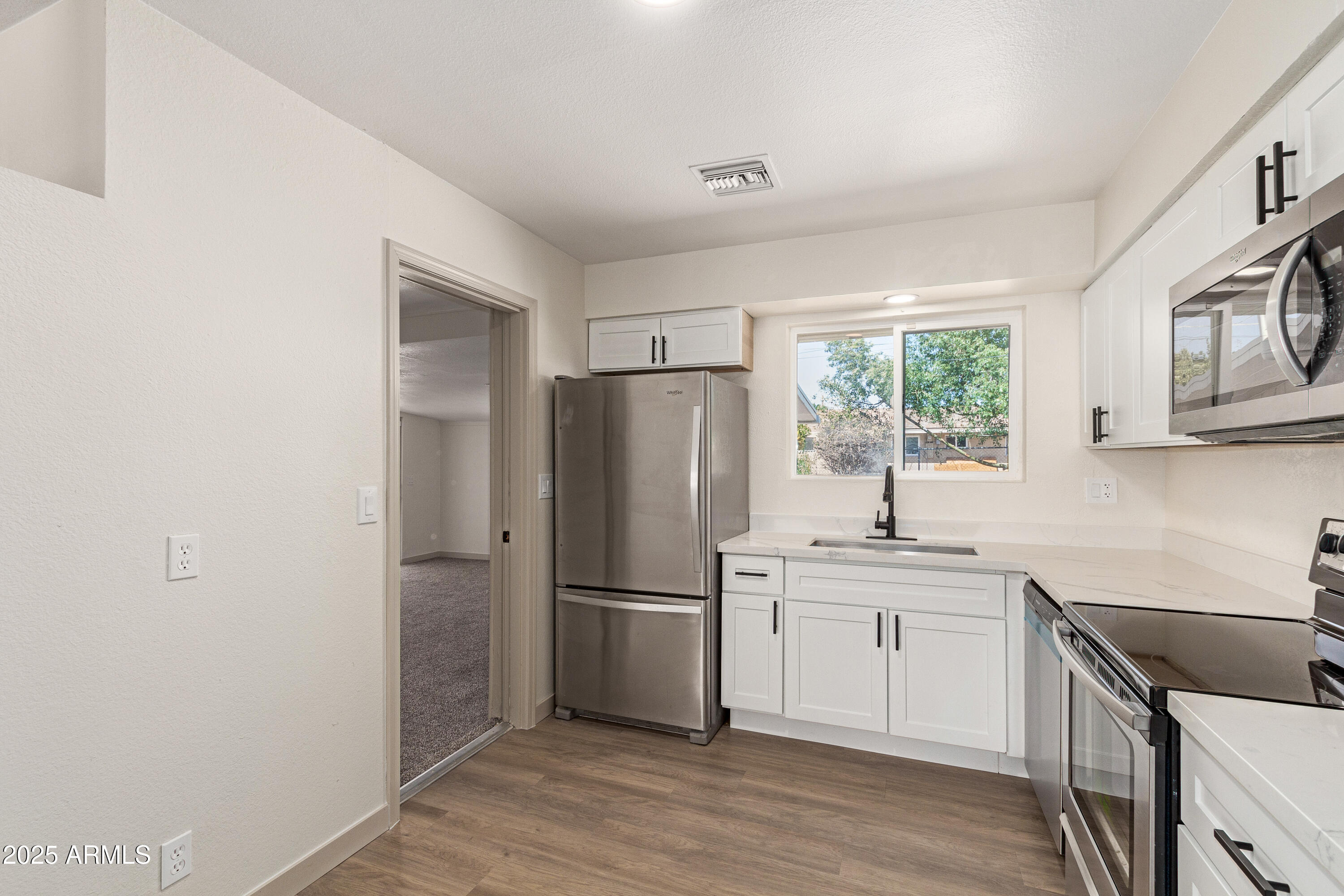 5732 Covina Road Mesa, AZ 85205 - Photo 8 of 24 a kitchen with stainless steel appliances a refrigerator sink and cabinets