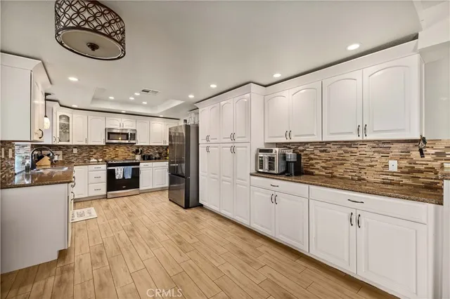 a kitchen with stainless steel appliances granite countertop a lot of counter space and wooden floors
