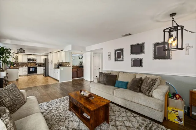 a living room with furniture wooden floor and kitchen view