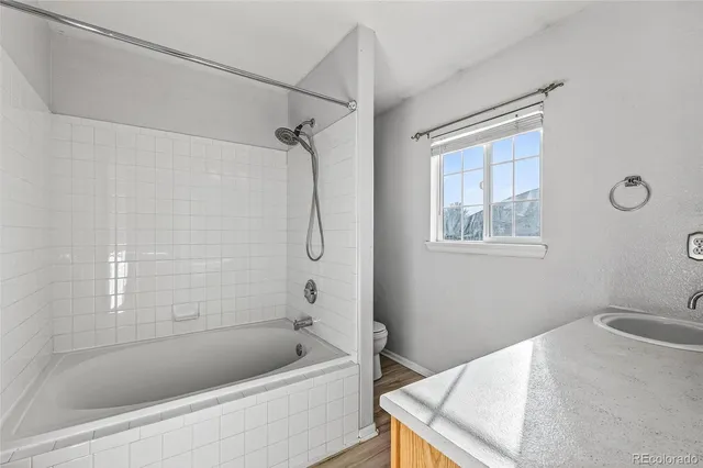a bathroom with a granite countertop sink a toilet and shower