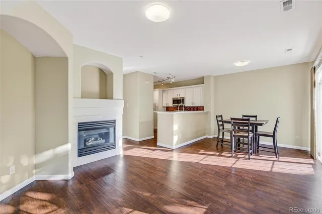 a living room with furniture a fireplace and a dining table with wooden floor