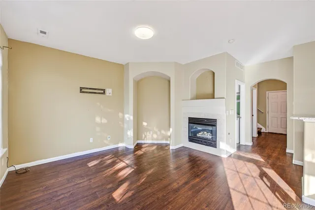 an empty room with wooden floor fireplace and windows