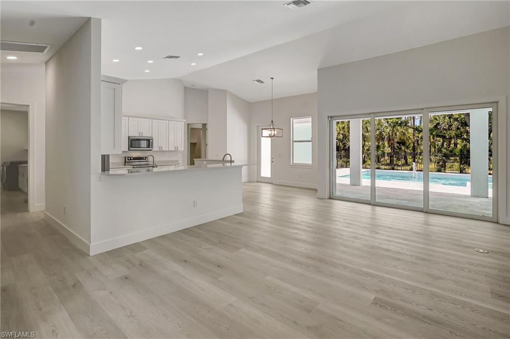 3390 12th Avenue Southeast Naples, FL 34117 - Photo 14 of 48 Unfurnished living room featuring high vaulted ceiling, baseboards, light wood-style flooring, and recessed lighting