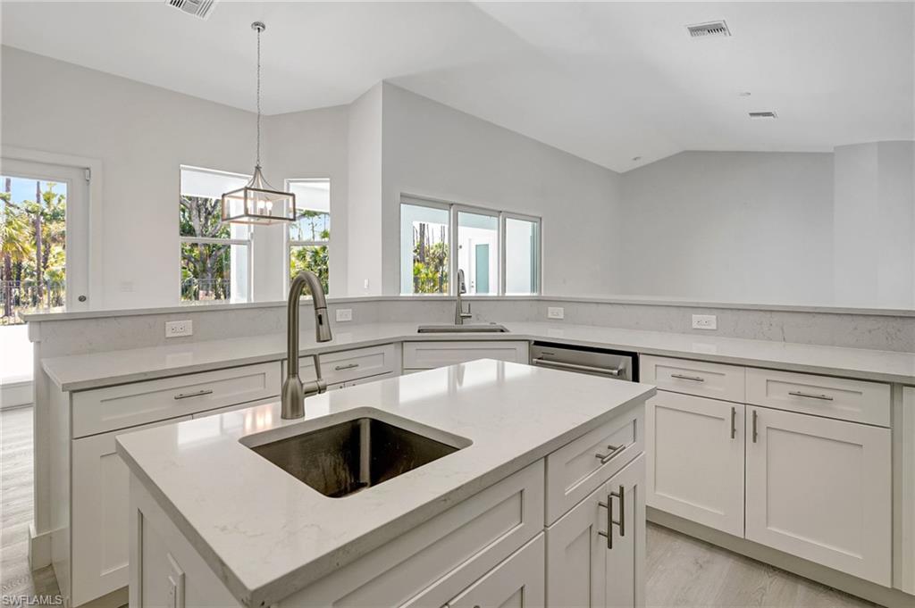3390 12th Avenue Southeast Naples, FL 34117 - Photo 17 of 48 Kitchen with a sink, an island with sink, white cabinets, and vaulted ceiling