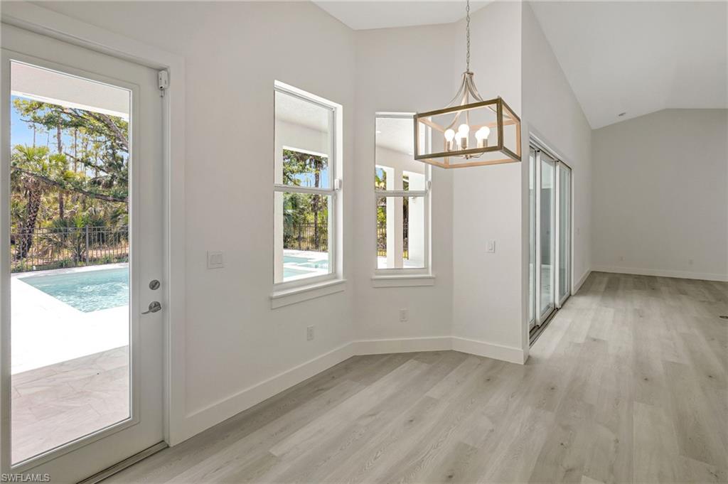 3390 12th Avenue Southeast Naples, FL 34117 - Photo 21 of 48 Unfurnished dining area featuring a chandelier, light wood-style flooring, lofted ceiling, and baseboards