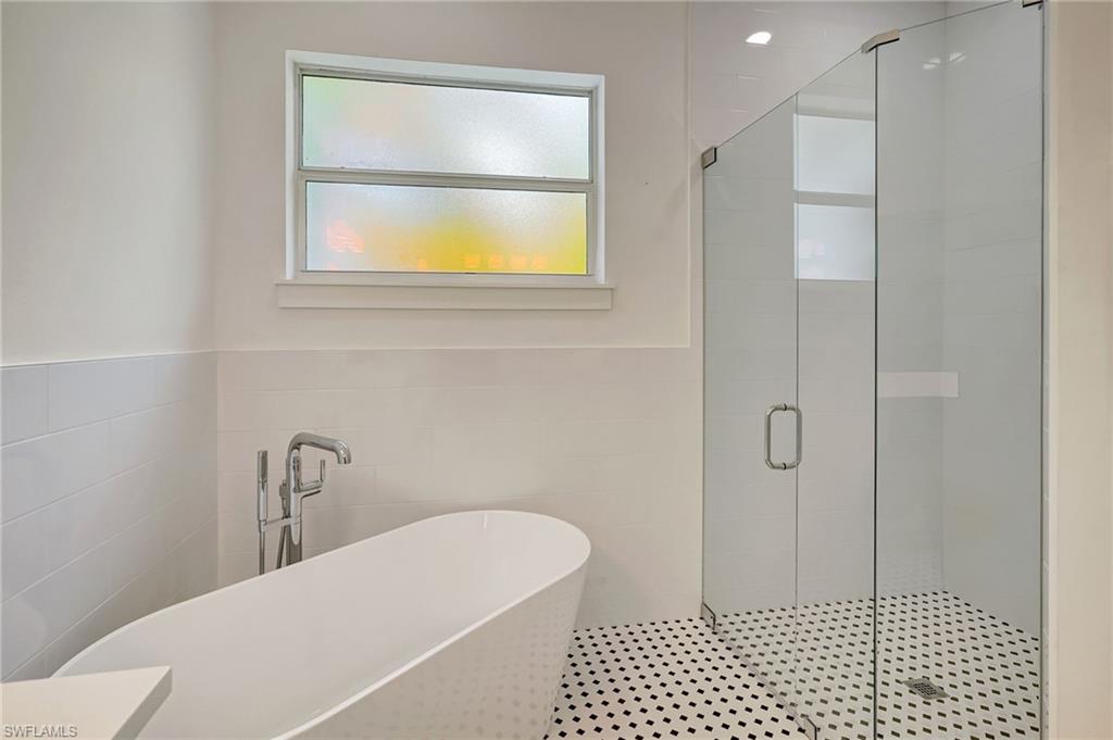 3390 12th Avenue Southeast Naples, FL 34117 - Photo 27 of 48 Full bath featuring tile walls, a shower stall, and a freestanding tub