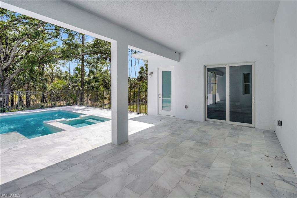 3390 12th Avenue Southeast Naples, FL 34117 - Photo 33 of 48 View of swimming pool featuring a patio, fence, and a pool with connected hot tub