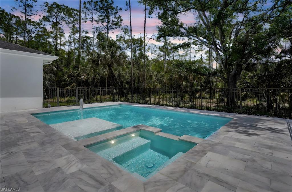 3390 12th Avenue Southeast Naples, FL 34117 - Photo 37 of 48 Pool at dusk featuring a pool with connected hot tub, fence, and a patio
