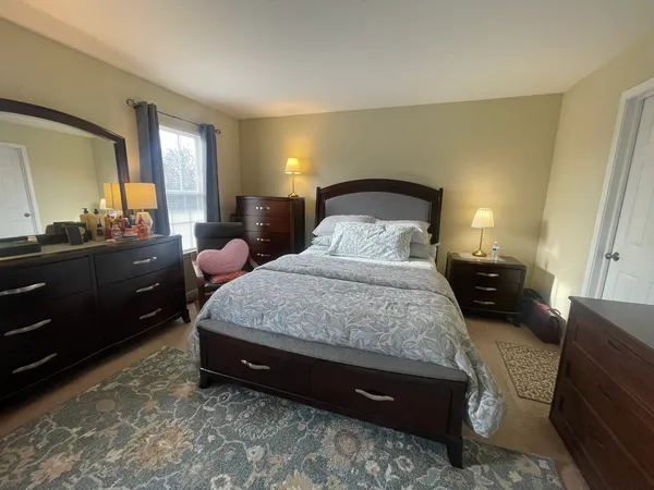 a spacious bedroom with a bed a lamp and dresser