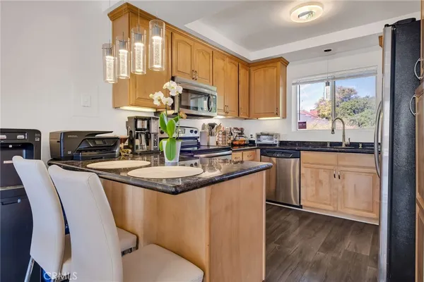 a kitchen with stainless steel appliances granite countertop a sink a stove cabinets dining table and chairs