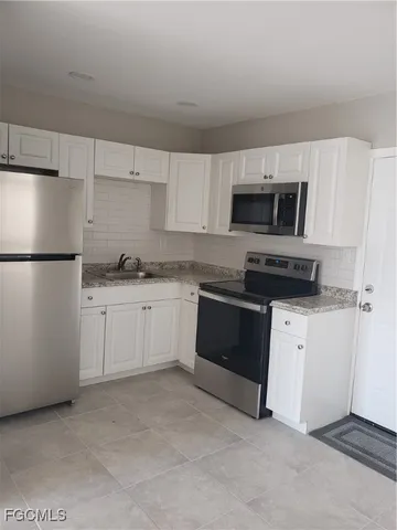 a kitchen with stainless steel appliances a refrigerator stove and white cabinets