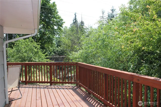 a balcony with wooden floor and trees in the background