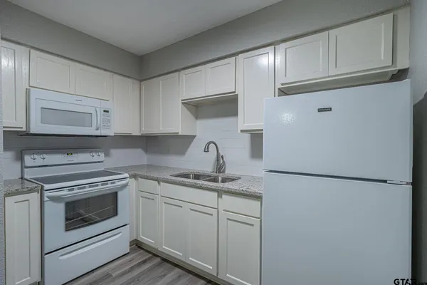 a kitchen with white cabinets and white appliances