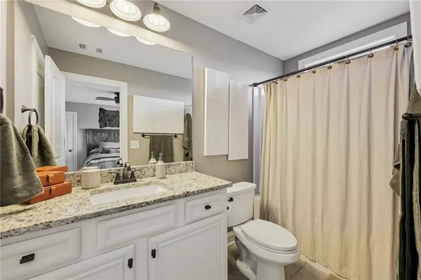 a bathroom with a granite countertop sink vanity mirror and toilet
