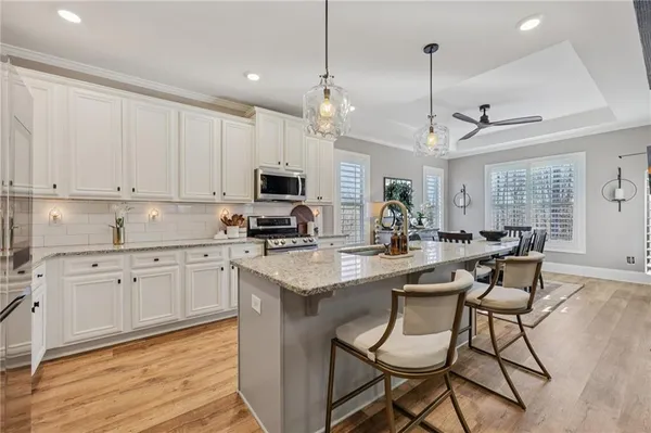 a kitchen with stainless steel appliances kitchen island granite countertop a sink a stove a dining table and chairs
