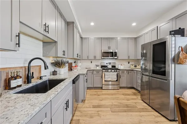 a kitchen with stainless steel appliances granite countertop a sink stove refrigerator and cabinets
