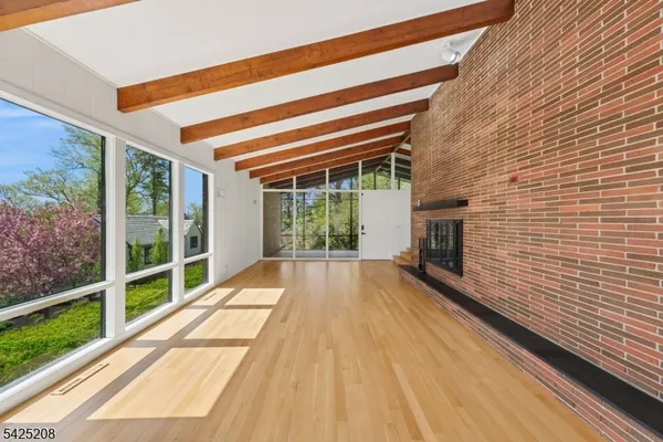 a view of an empty room with wooden floor and windows