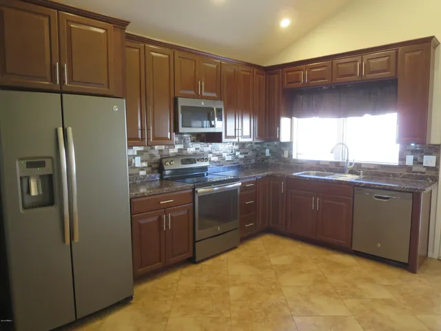 a kitchen with stainless steel appliances granite countertop a refrigerator a sink dishwasher a stove top oven a sink and dishwasher