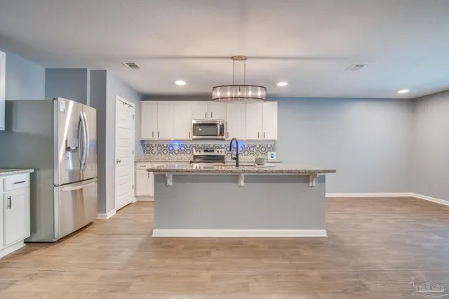 a view of a kitchen with refrigerator and wooden floor