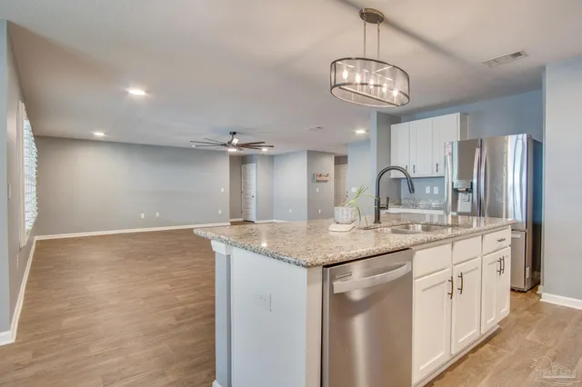 a kitchen with stainless steel appliances granite countertop a sink a refrigerator and a stove