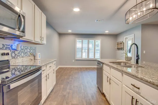 a kitchen with a sink appliances cabinets and a window