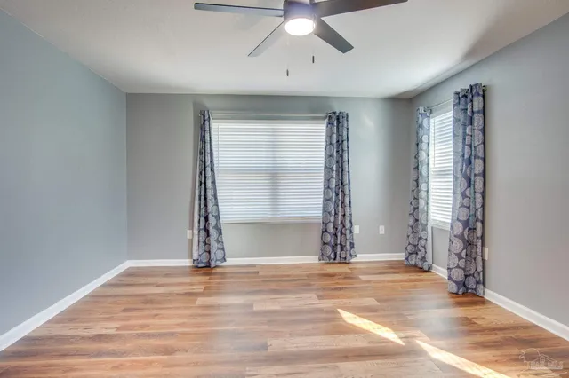 an empty room with wooden floor and windows