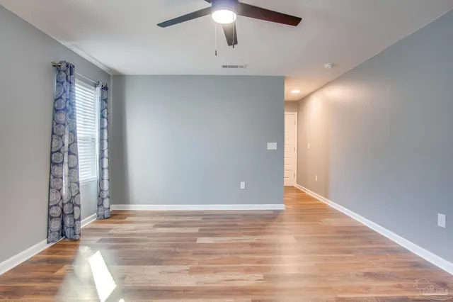 a view of an empty room with window and wooden floor