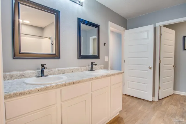 a bathroom with a granite countertop double vanity sink and mirror