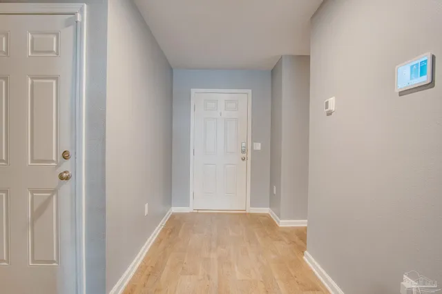 a view of a hallway with wooden floor and a bathroom