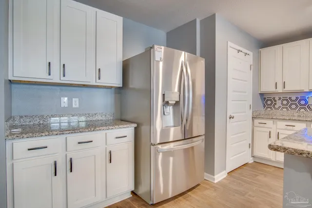 a kitchen with stainless steel appliances granite countertop a refrigerator and white cabinets