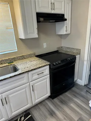 a kitchen with granite countertop white cabinets and black appliances