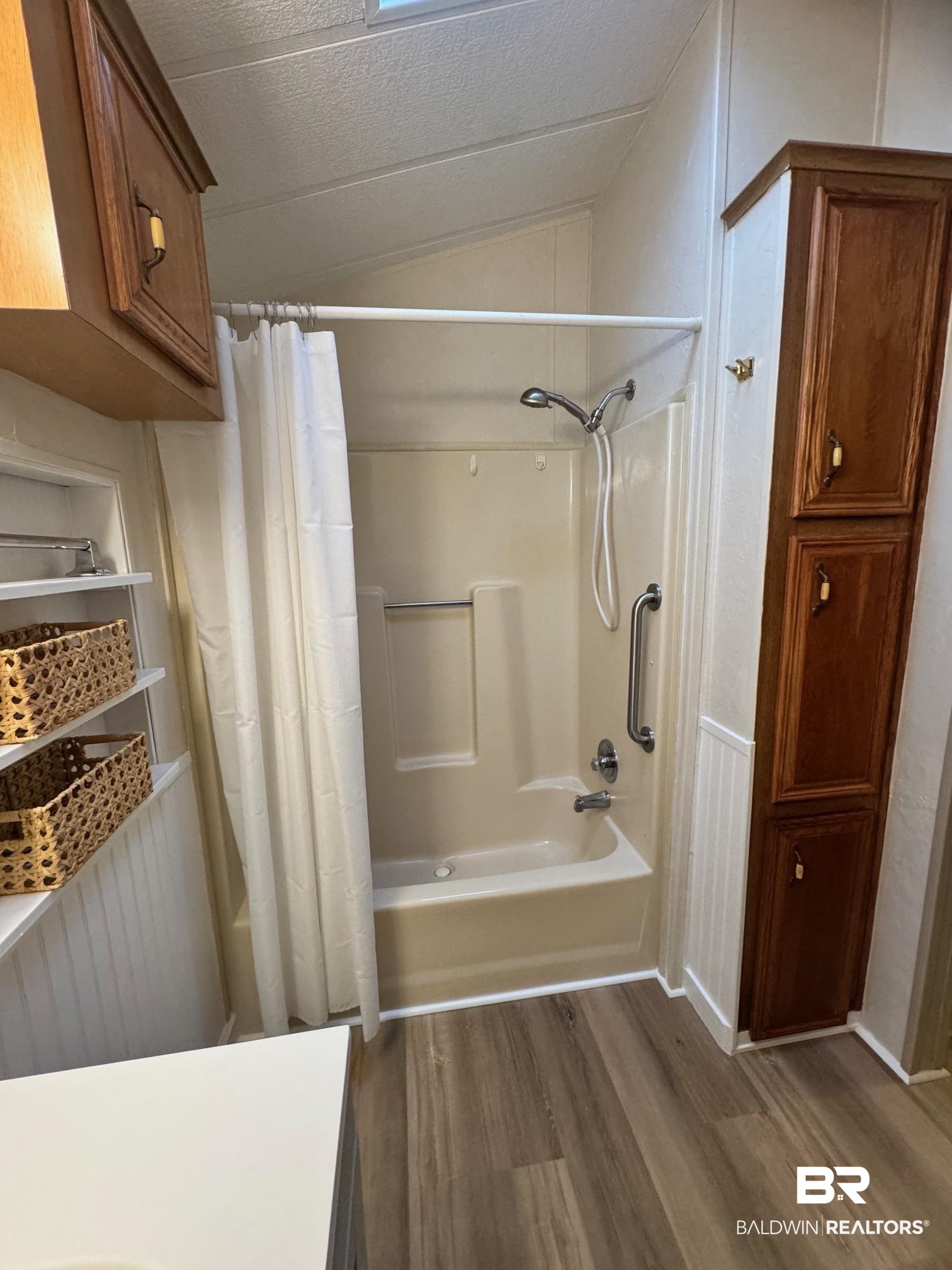 195 Defuniak Loop Lillian, AL 36549 - Photo 12 of 37 Full bath featuring shower / bathtub combination with curtain, wood finished floors, and vaulted ceiling