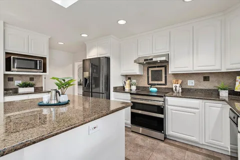 a kitchen with stainless steel appliances granite countertop a sink a stove and a granite counter tops