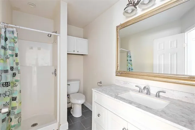 a bathroom with a granite countertop toilet a sink a shower and a mirror