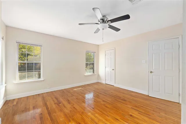 a view of empty room with wooden floor and fan