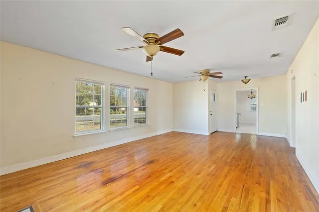 a view of empty room with wooden floor and fan