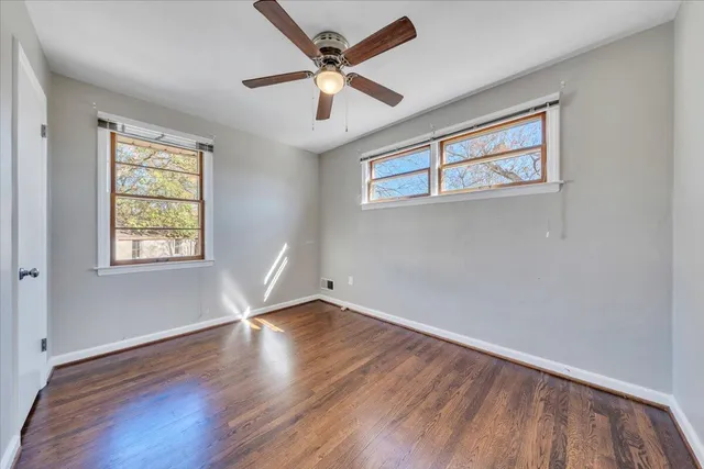 a view of empty room with wooden floor and fan