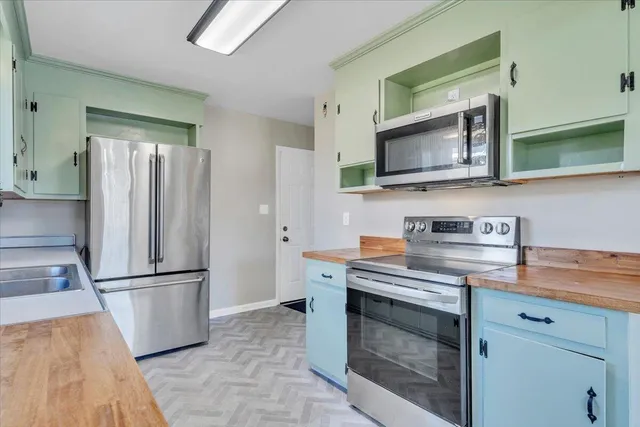 a kitchen with granite countertop a refrigerator and a stove top oven