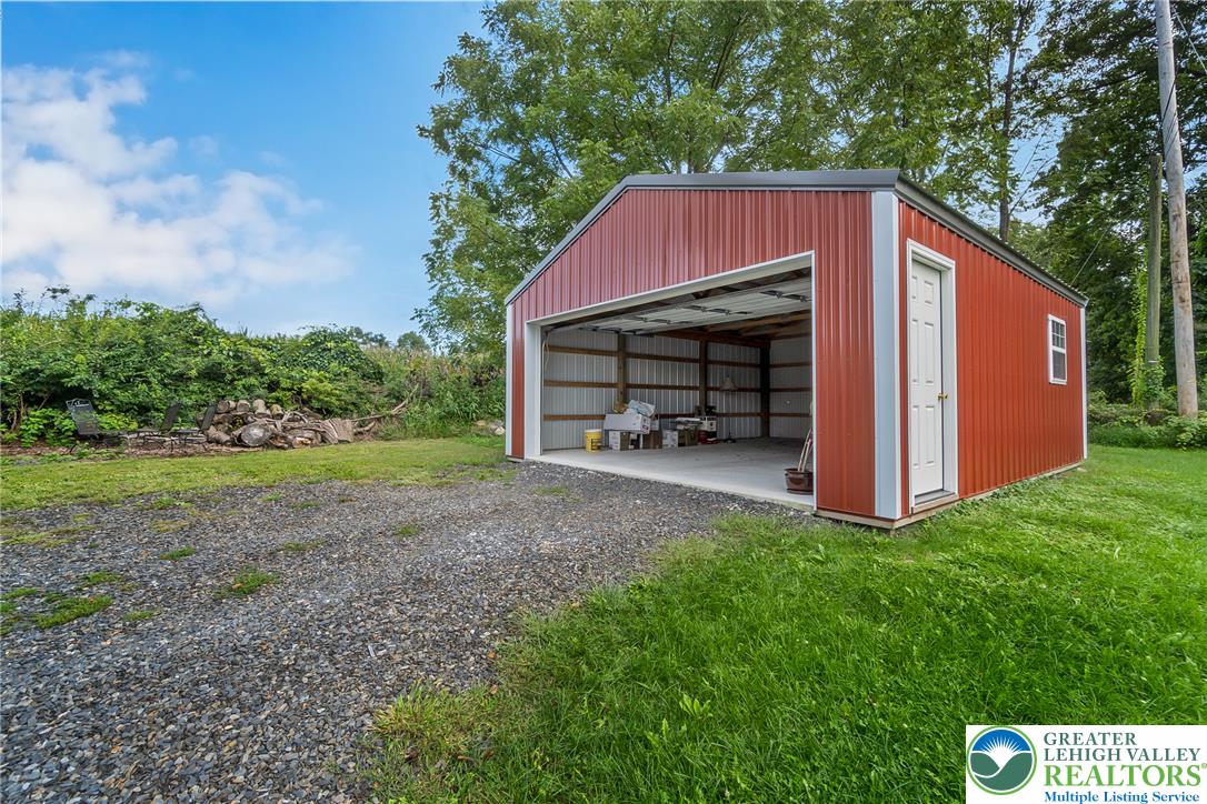 506 Richmond Road Bangor, PA 18013 - Photo 5 of 43 A spacious metal outbuilding sits on a gravel driveway surrounded by lush greenery.