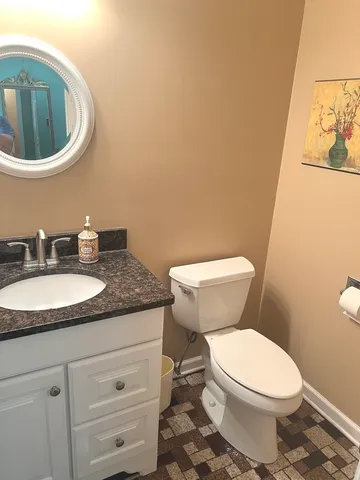 a bathroom with a granite countertop toilet and a sink