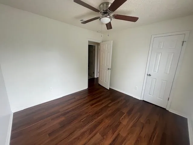a view of empty room with wooden floor and fan