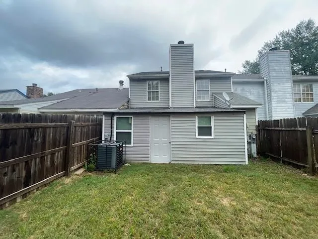 a view of a backyard with wooden fence and large trees