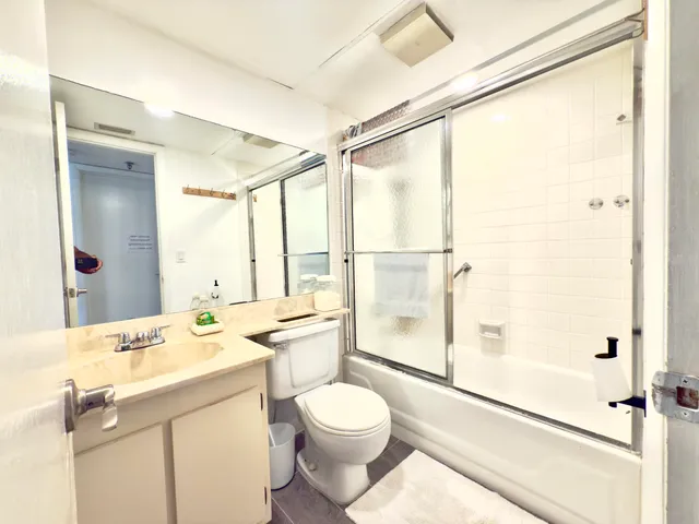 a bathroom with a granite countertop sink toilet mirror and shower