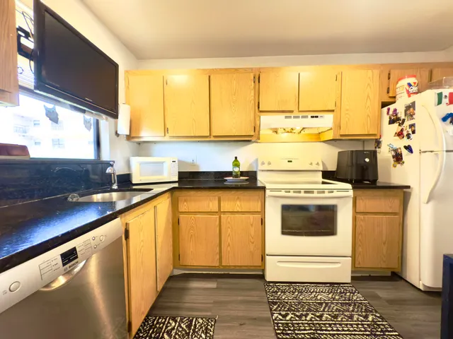 a kitchen with a stove a sink and white cabinets with wooden floor