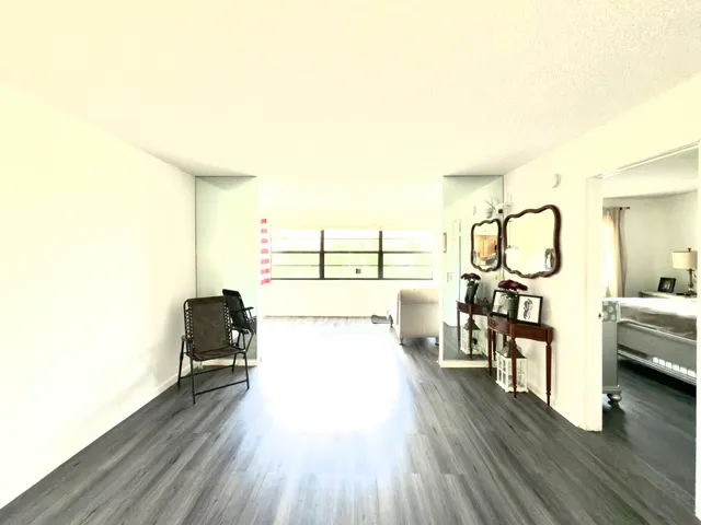 a living room with furniture a mirror and wooden floor